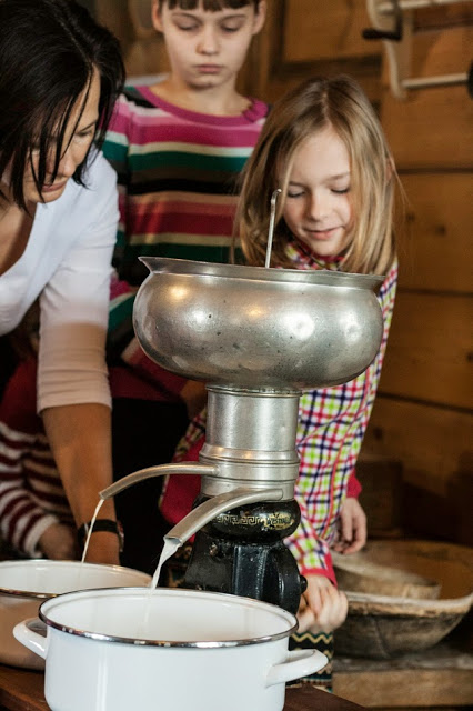 Dzieci z opiekunem patrzące na urządzenie do wyrobu mleka