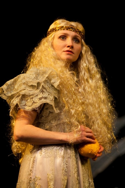 Aktorka z bogatymi i bujnymi blond lokami trzymająca okrągły, żółty przedmiot
