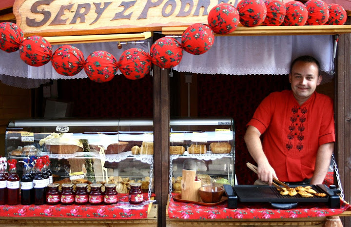 Mężczyzna ubrany na czerwono przy stoisku z serami