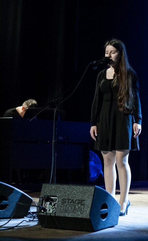 Dziewczyna w czarnej sukience śpiewająca do mikrofonu