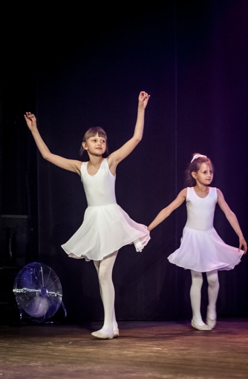 Dwie dziewczynki ubrane jak białe baletnice występują na scenie