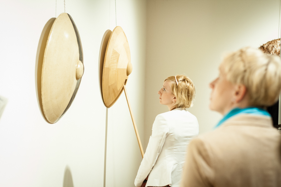 Kobiety patrzące na dwie wywieszone na białej ścianie beżowe okrągłe tarcze