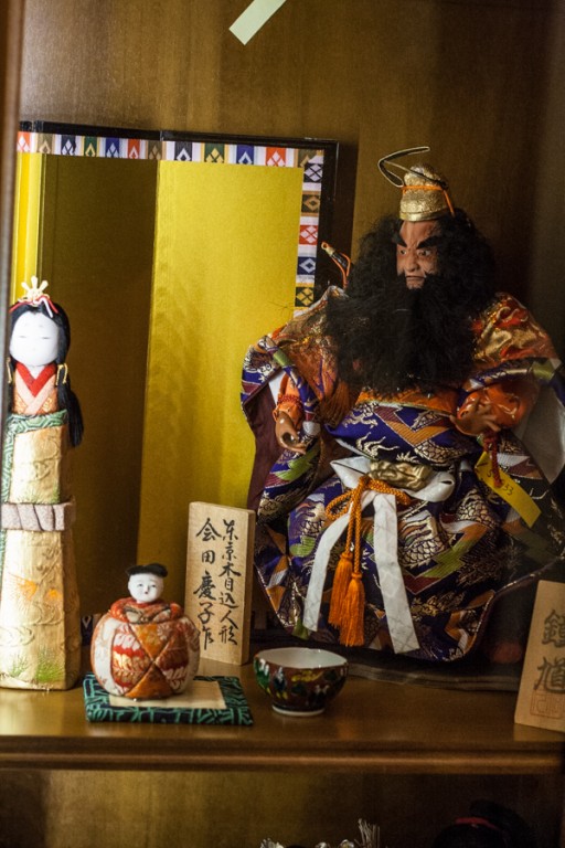 Lalka przedstawiająca brodatego mężczyznę ubranego w historyczny, azjatycki strój, obok niego na półce różne inne przedmioty nawiązujące do tej kultury