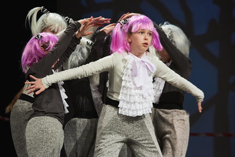 Dzieci ubrane w fioletowe i białe peruki występujące na scenie