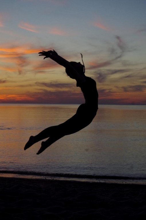 Sylwetka skaczącej tancerki na tle zachodu słońca nad morzem