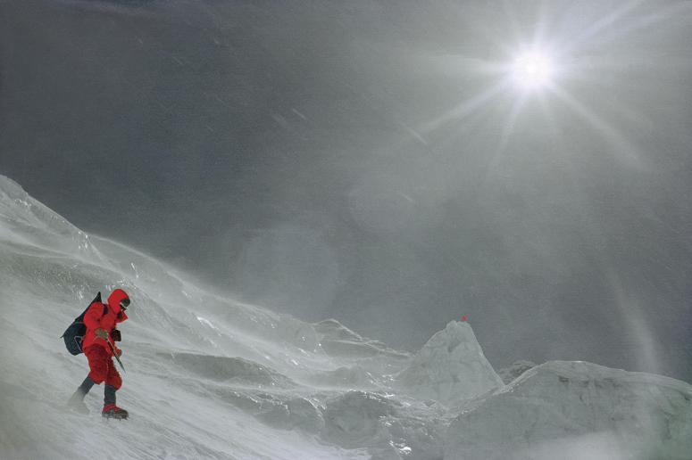 Osoba w czerwonym zimowym stroju idzie po śnieżnym terenie w słoneczny dzień