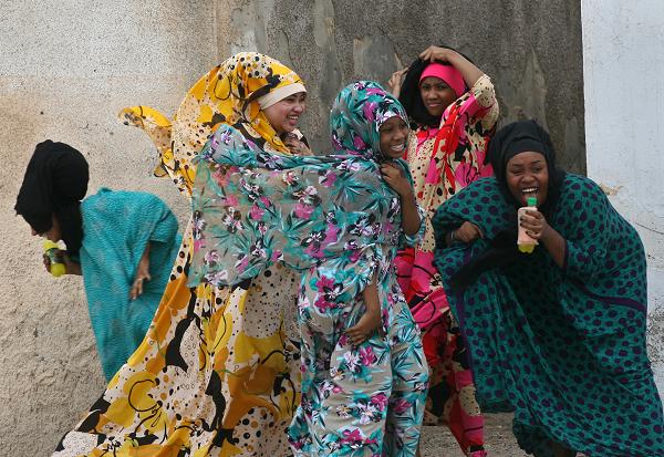 Ciemnoskóre kobiety ubrane w kolorowe kwiatowe chusty śmieją się razem