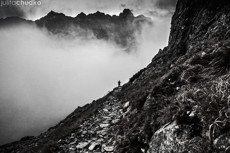 Czarno-białe zdjęcie wzniesienia góry, w oddali gęsta mgła