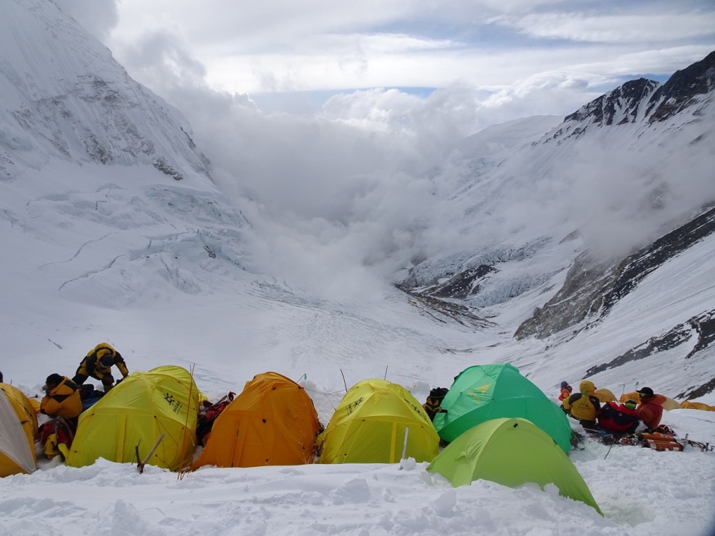 Namioty i alpiniści u szczytu ośnieżonych gór