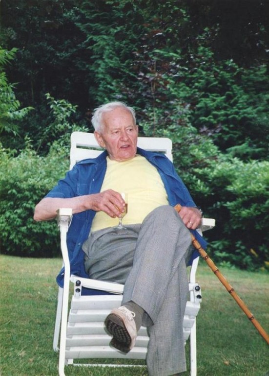Starszy mężczyzna siedzący na białym leżaku na tle podwórka