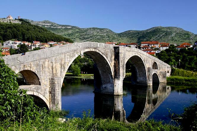 Most nad wodą prowadzący do małego miasteczka przy wzgórzach