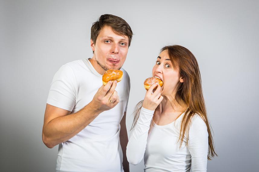 Kobieta z mężczyzną ubrani na biało jedzą pączki