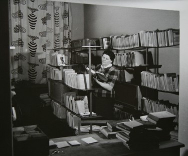 Kobieta czytająca książkę w bibliotece