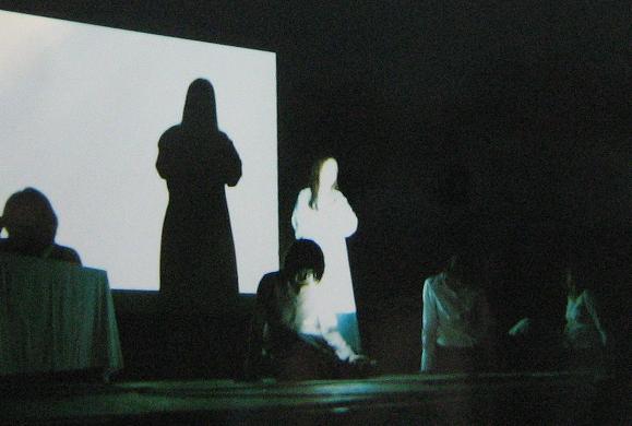 Występ na scenie z ostrym światłem robiący wyraźne cienie na ścianie
