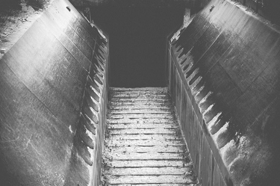 Zdjęcie przedstawia schody prowadzące w głąb ciemnego korytarza