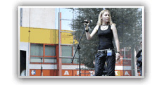Kobieta stoi przy mikrofonie, w tle widać budynek