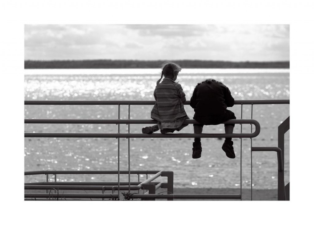 dwie dziewczynki na poręczy przy jeziorze