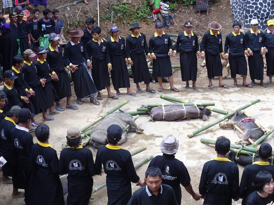 Azjaci stojący w kółku wokół martwych zwierząt obwiązanych bambusem