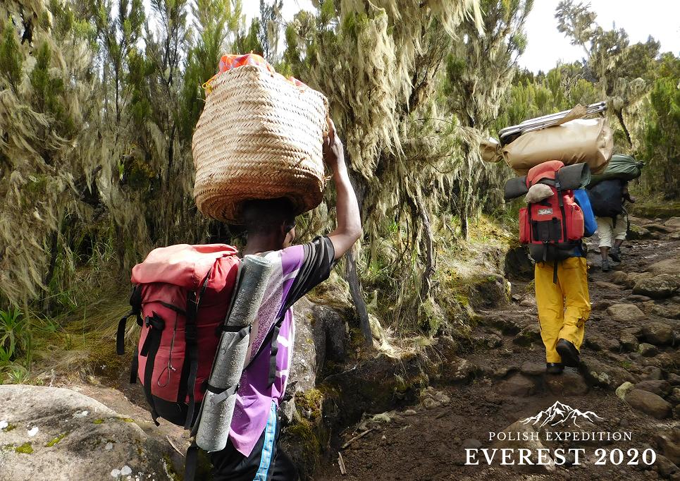 Zdjęcie promocyjne polish expedition everest 2020 ciemnoskórzy mężczyźni z plecakami i koszami na głowie