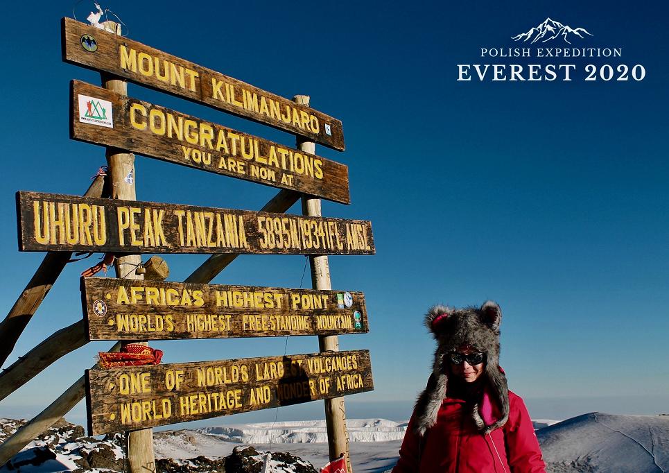 Kobieta z czapką z uszami koło drogowskazów Killimanjaro, najwyższy punkt afryki