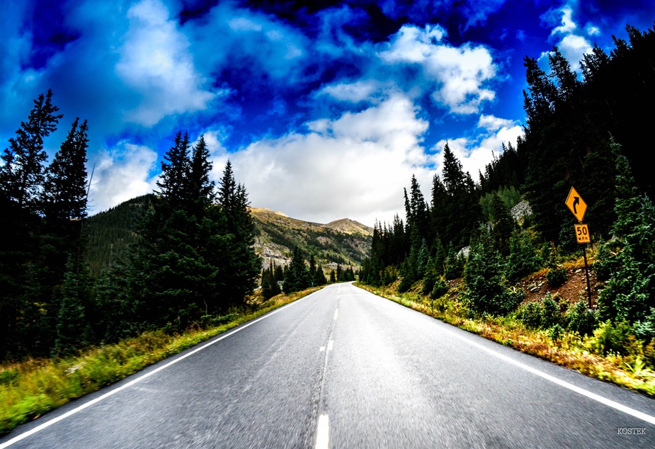 Zdjęcie drogi między zielenią, w tle góry