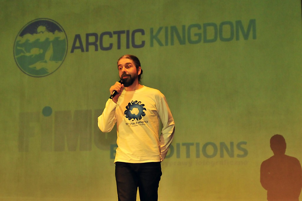 Mężczyzna w koszulce z logo przemawiający do mikrofonu