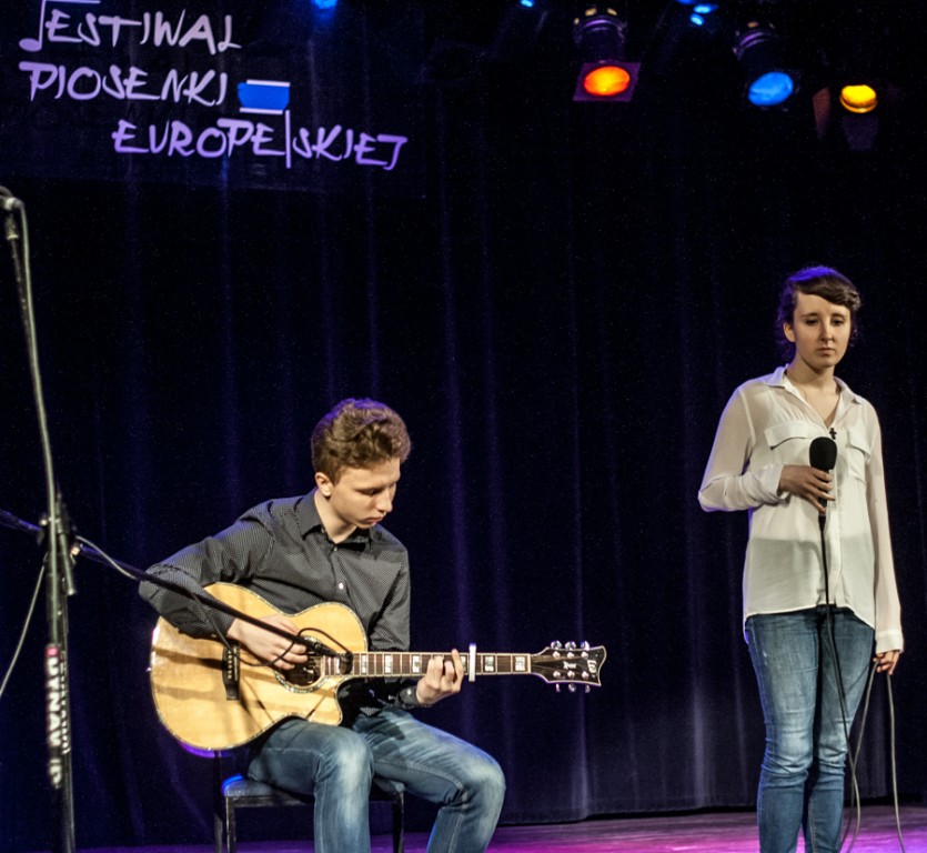 Mężczyzna grający na gitarze, obok niego kobieta trzymająca mikrofon