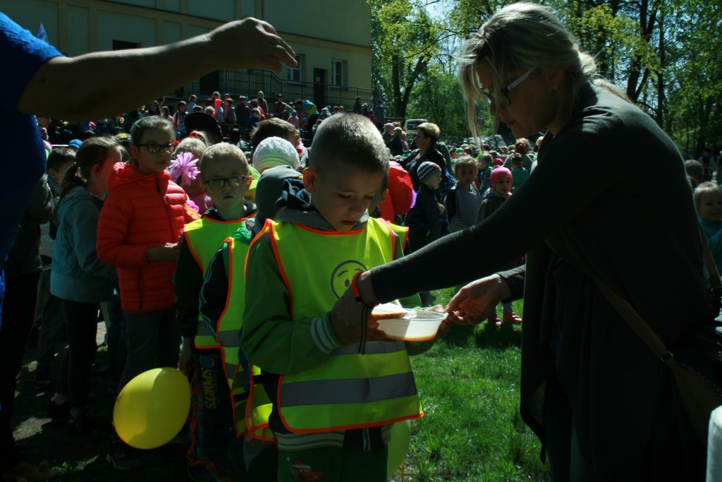 Kobieta podająca zupę w plastikowej miseczce dzieciom stojącym w kolejce