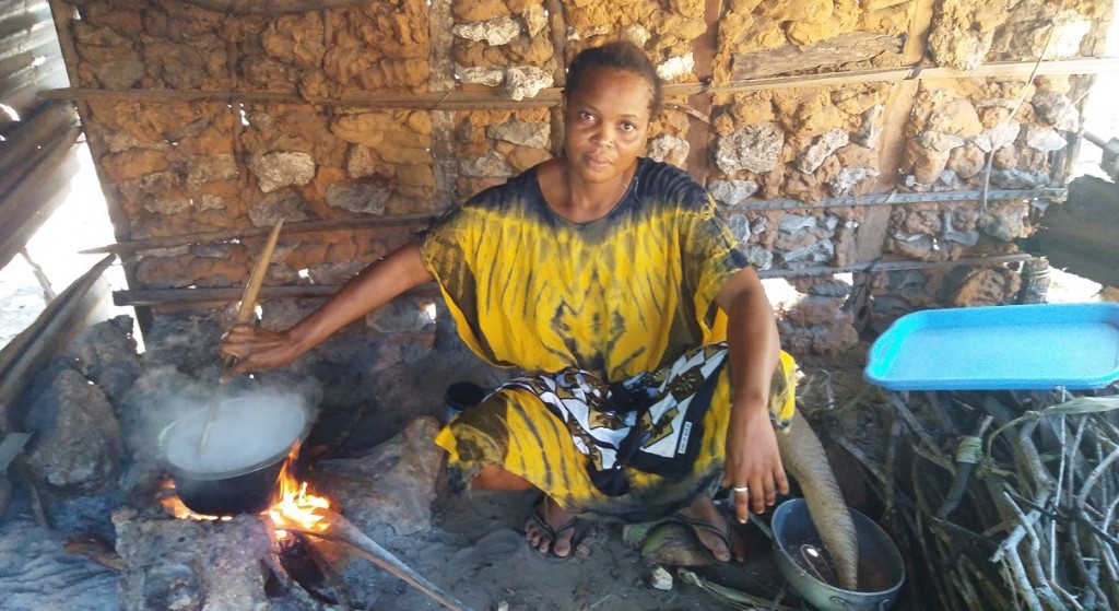 Ciemnoskóra kobieta przy gotującej się nad ogniskiem wodzie
