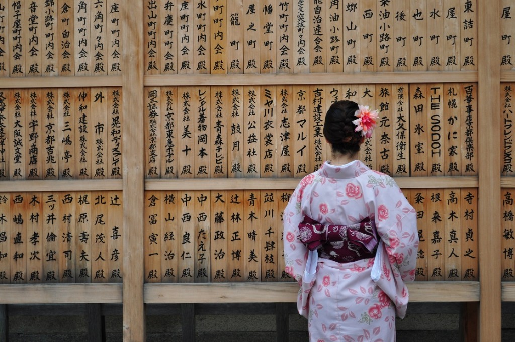 Kobieta przy drewnianej ścianie z zapisanymi japońskimi słowami