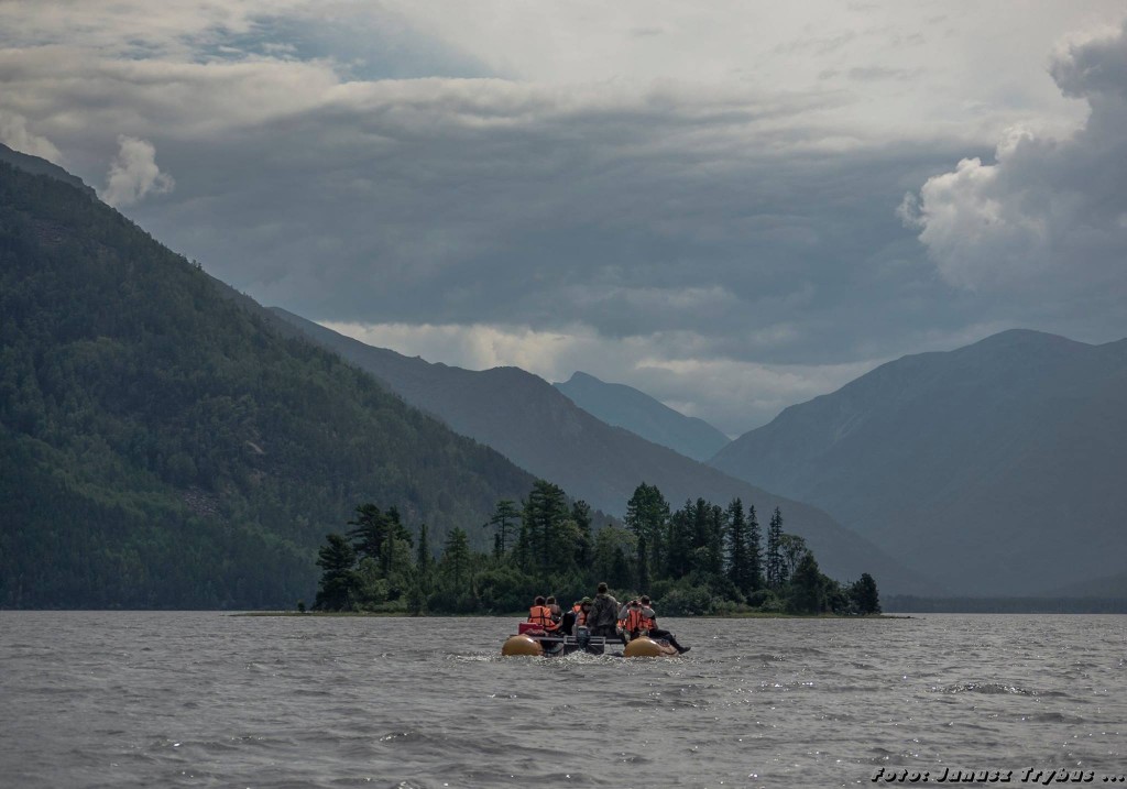 Ludzie na pontonie płynący do wysepki na jeziorze wśród gór