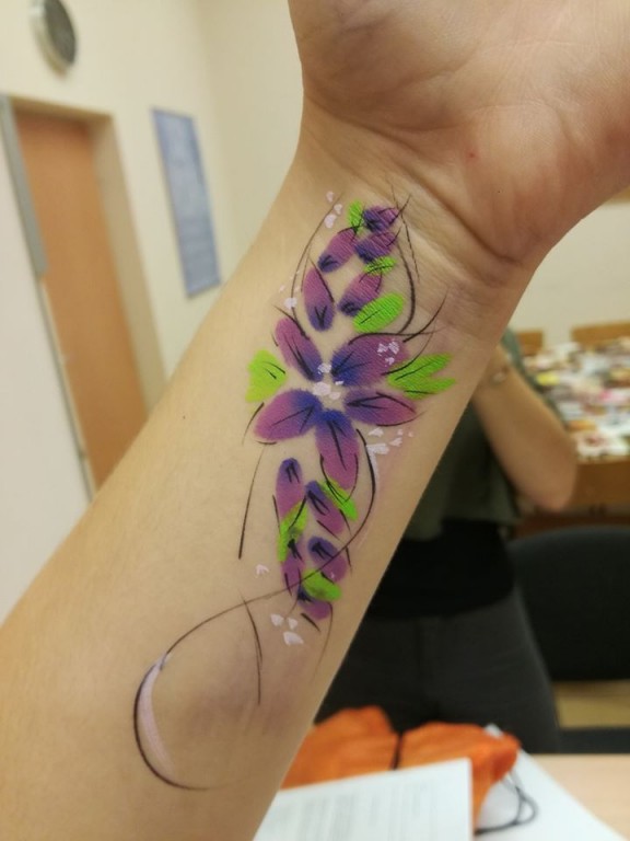 Ręka z wytatuowanym kolorowym kwiatkiem