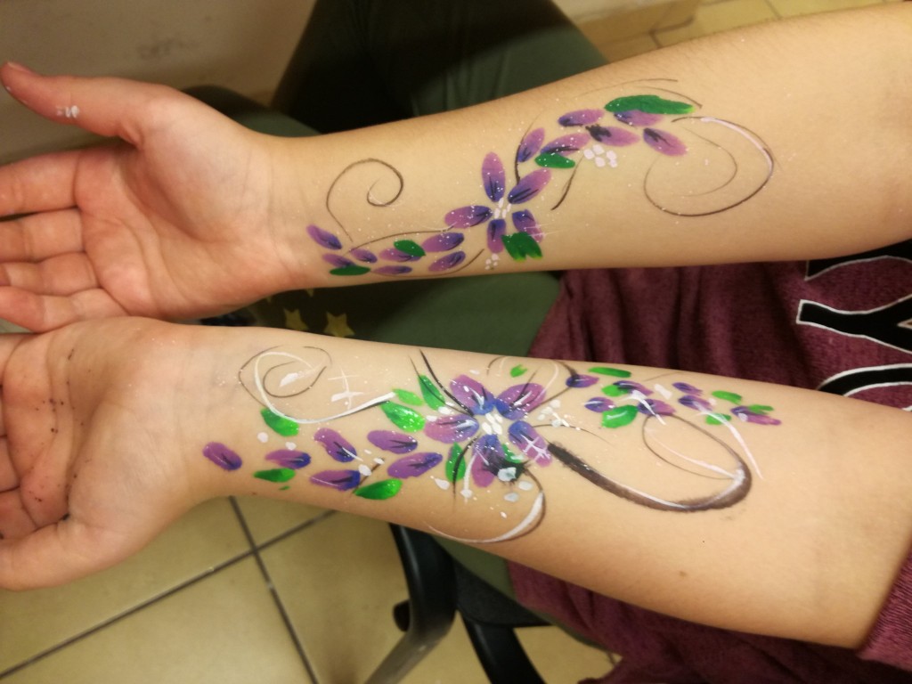Dwie ręce z wytatuowanymi kolorowymi kwiatkami