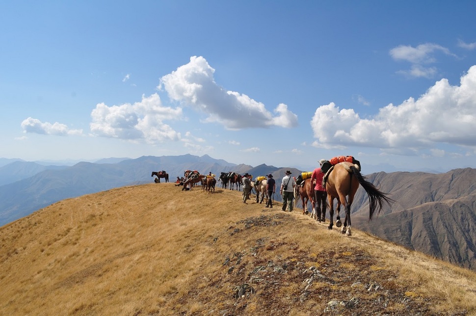 Ludzie na koniach przechodzący po szczycie góry
