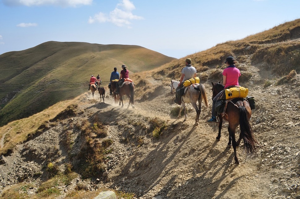 Ludzie na koniach przechodzący po górach
