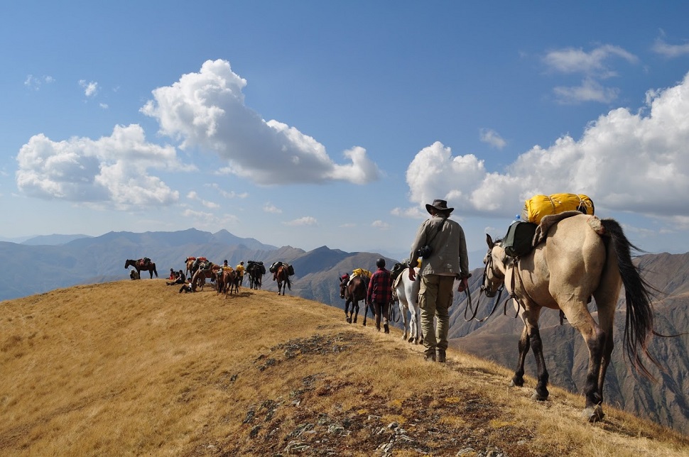 Ludzie na koniach przechodzący po szczycie gór