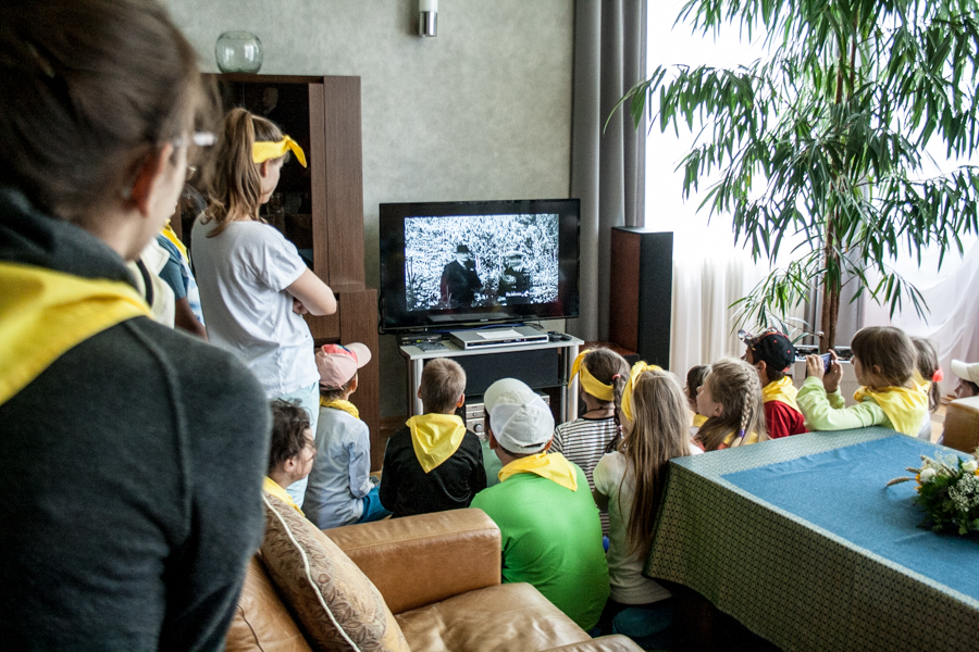 Dzieci w żółtych chustach oglądające film na telewizorze