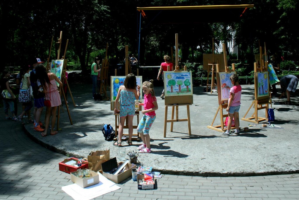Dzieci ze sztalugami malujące w parku