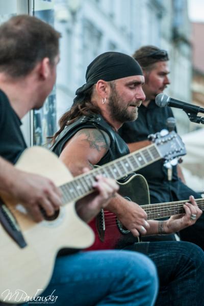 Trzech mężczyzn grających na gitarach na scenie