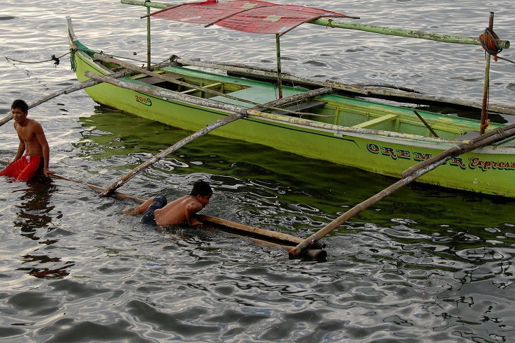 Ludzie trzymający się belek wystających z łodzi nad wodą
