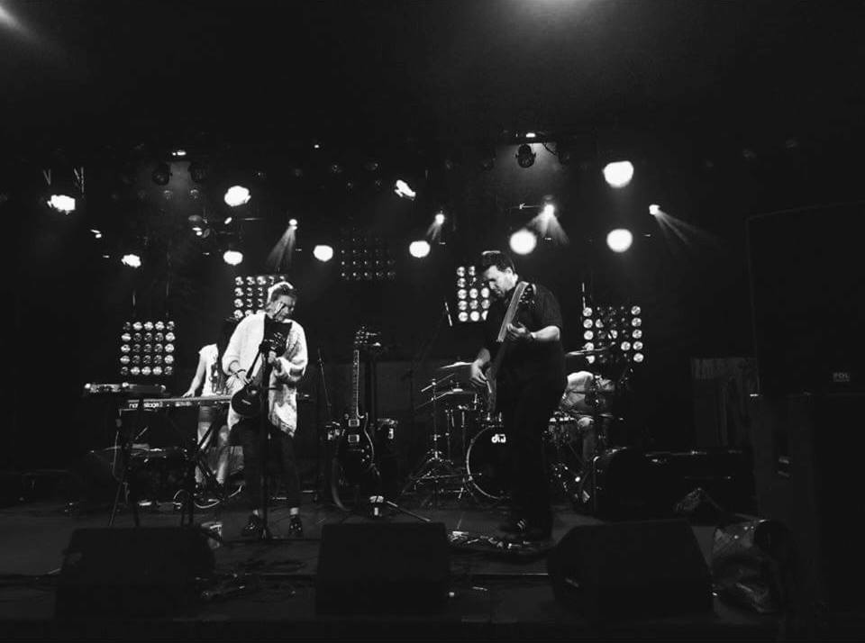 Czarno-białe zdjęcie zespołu muzycznego grającego na scenie