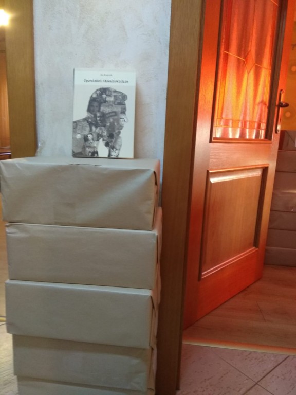 Książka opowieści chwałowickie stojąca na stosie kartonów obok drzwi