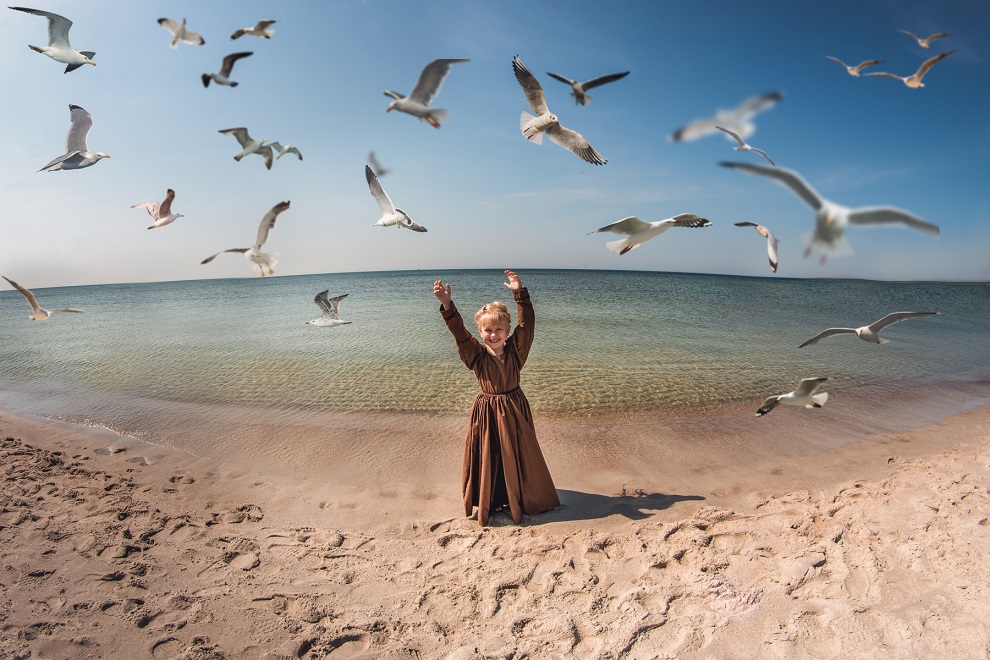 Dziewczynka na plaży wśród latających mew