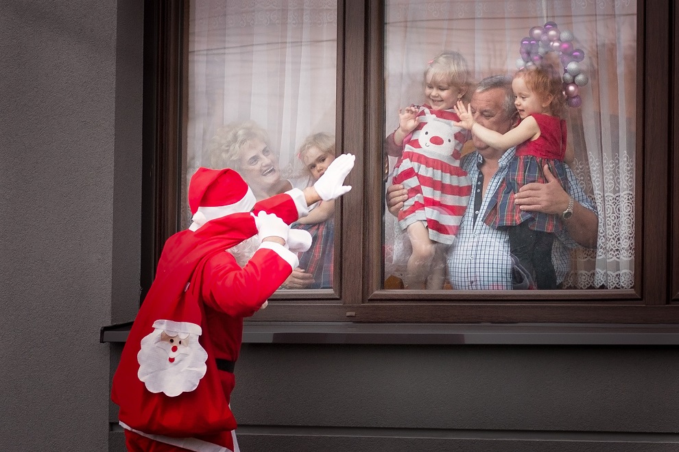 Dzieci z dziadkami machające mikołajowi przez okno, mikołaj odmachuje