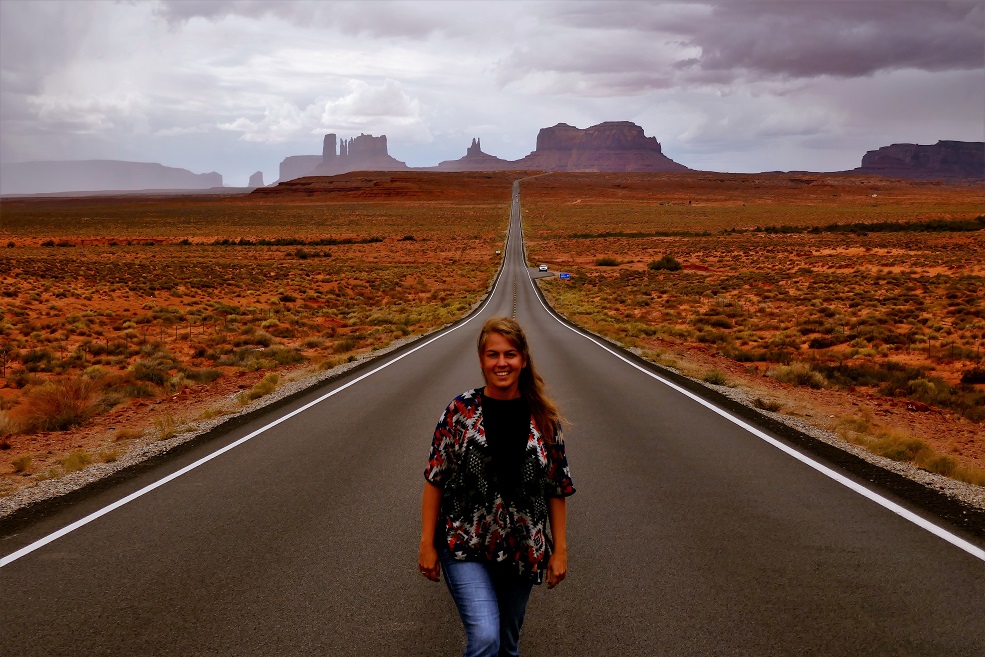 Kobieta na środku drogi, w około stepy i pomarańczowe góry