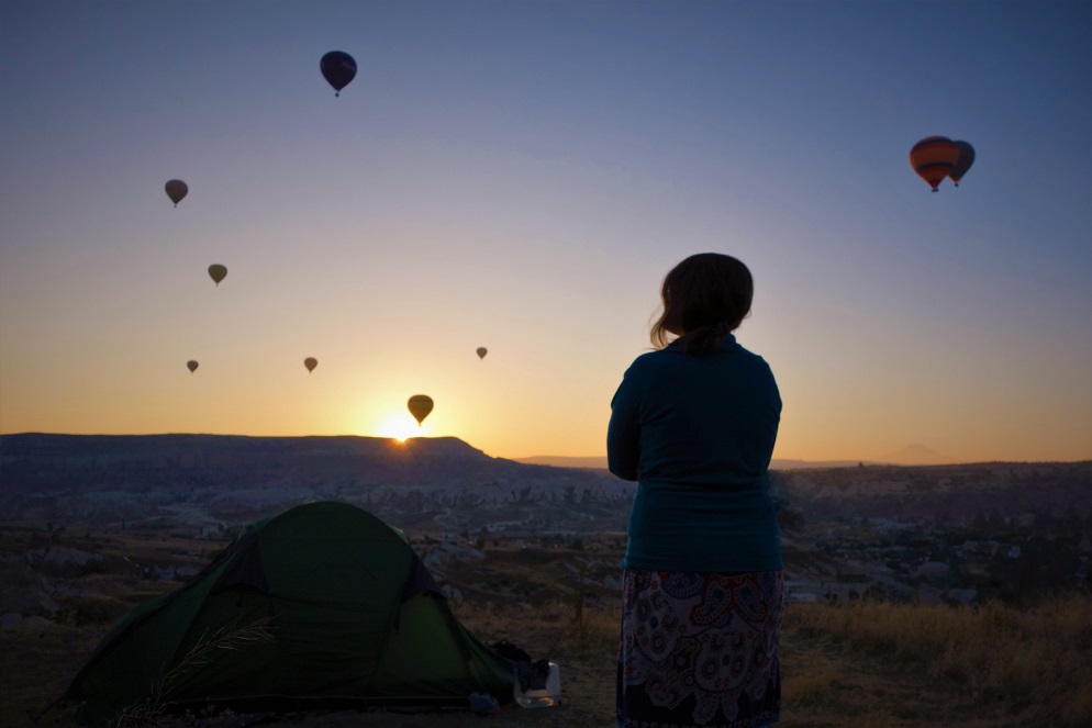 Namiot na stepie i kobieta podziwiająca balony