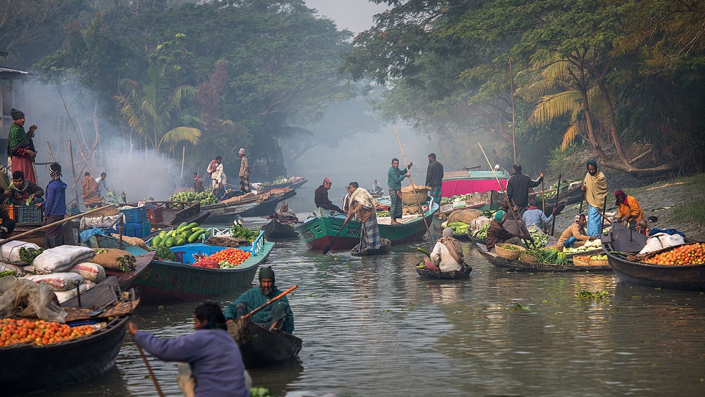 Hindusi i łódki wypełnione owocami i warzywami na rzece