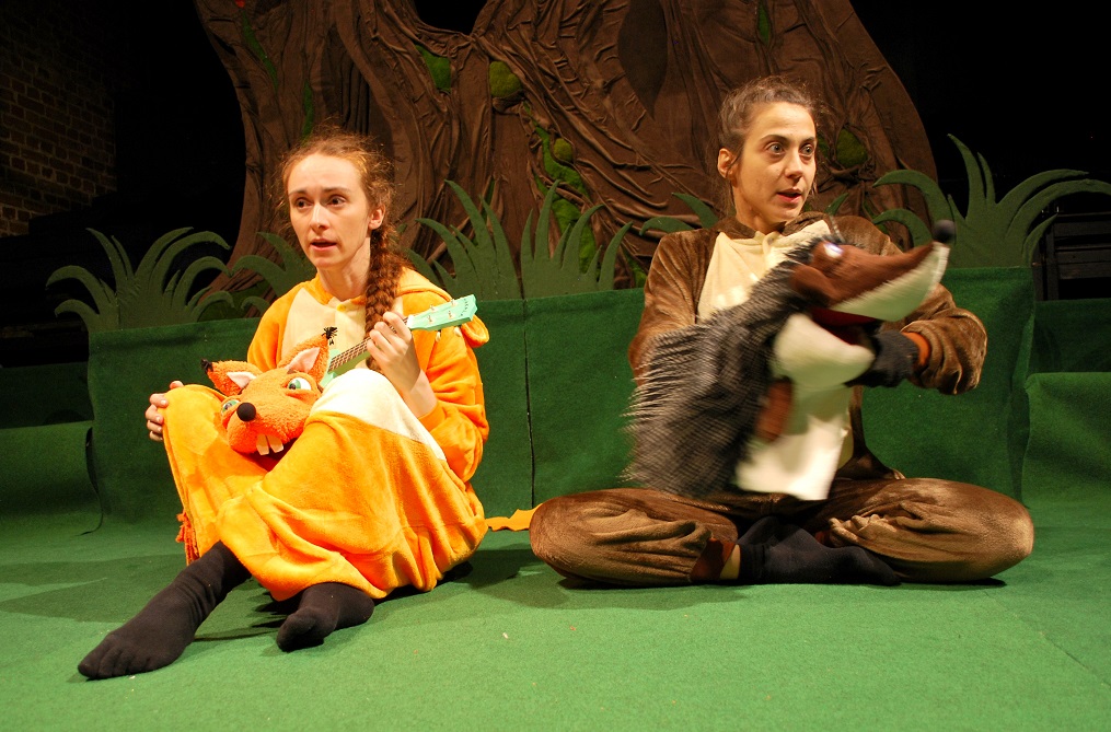 Aktorka z pacynką lisa przebrana za lisa i aktorka z pacynką jeża przebrana za jeża, siedzą obok siebie