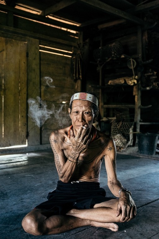 Azjata ze skrzyżowanymi nogami palący papierosa, na głowie biała opaska