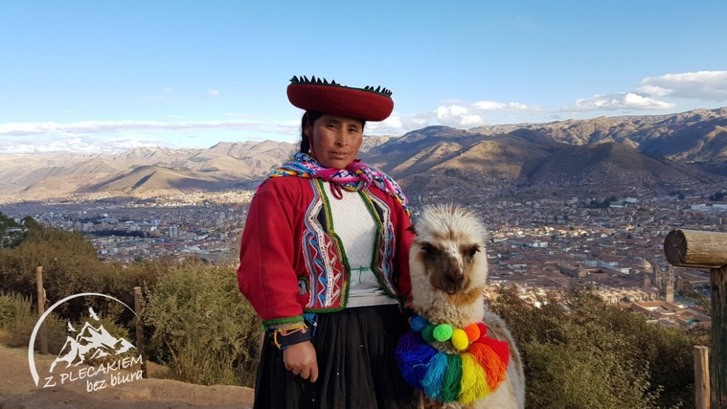 Kobieta w stroju ludowym z lamą z kolorowymi pomponami Ameryka Południowa